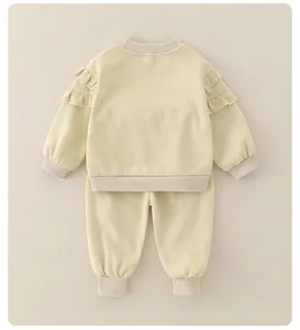 Detail of infant beige cotton set with ruffle shoulder accents and ribbed cuffs