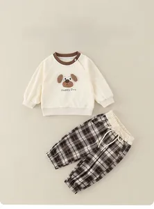 Detail of baby cotton set with puppy embroidery and plaid trousers on plain background