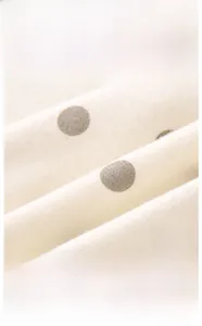 Close-up of Class A cotton fabric for infant bodysuits with brown polka dot pattern