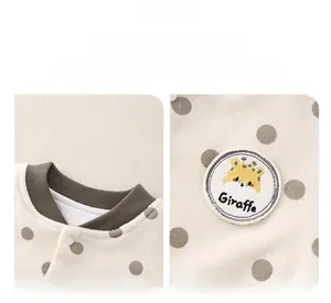 Detail of baby romper featuring beige knit fabric, grey polka dots and giraffe embroidery