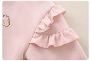 Detail of baby girl pink knit top with ruffled sleeves and cute cartoon embroidery