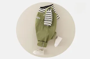 Detail showing hand made label on olive green cotton overalls with striped tee shirt