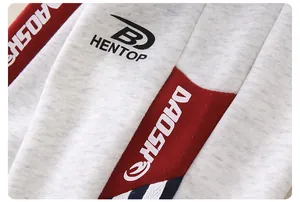 Detail of grey knitted baby sweatshirt featuring red and navy contrast patchwork with HENTOP logo