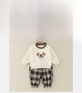 Detail of baby set showing cream sweatshirt with dog print and brown plaid trousers
