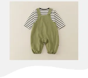 Detail view of army green cotton baby overalls and striped long sleeve set on cream background