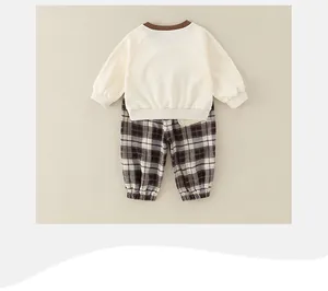 Flat lay detail of cute two-piece infant set with beige top and brown checkered pants