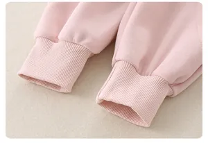 Detailed close-up of ribbed cuffs and soft pink cotton knit fabric on baby sweatshirt