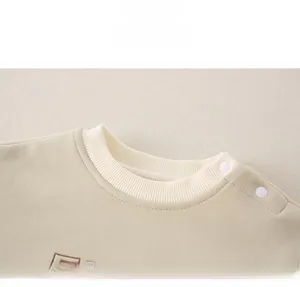 Detailed close-up of ribbed collar and shoulder snap buttons on cotton baby sweatshirt