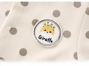 Close-up of knit baby romper featuring grey polka dots and a giraffe embroidery patch