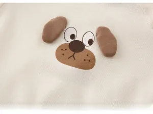 Detailed macro view of the ribbed fabric and puppy applique on baby's cream outfit