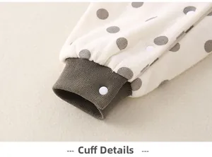 Close-up of olive green ribbed leg cuffs on beige polka dot baby romper with snap button