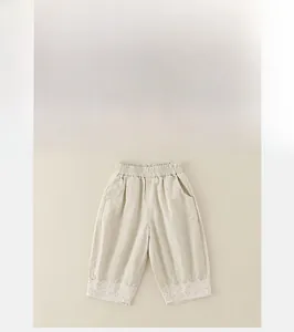 Detail of baby girl cotton trousers featuring elastic waistband and delicate lace trim hem
