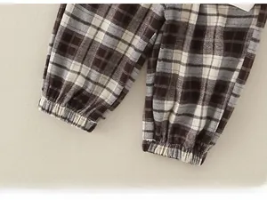 Detail shot of baby plaid trousers featuring elastic cuffs and classic brown check fabric