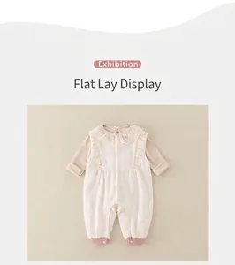 Detailed flat lay of a beige infant romper featuring lace ruffles and pink ribbed cuffs