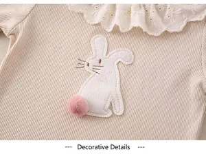 Detail of baby girl outfit with lace collar, rabbit embroidery and plush tail detail