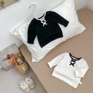 Dettaglio della maglia a maniche lunghe bimba con colletto a contrasto e fiocco