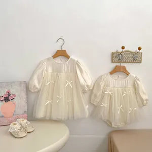 Detail view of cream long sleeve tulle dress and bodysuit with bow accents for baby girls