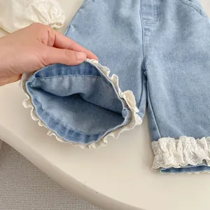 Girls light blue denim wide leg jeans featuring elegant white lace hem details