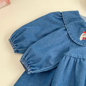 Close-up of a blue denim dress collar with cute rabbit embroidery and ruffled detail