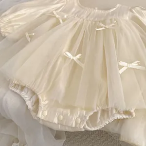 Close-up of baby girl beige romper with layered mesh skirt and satin bows detail