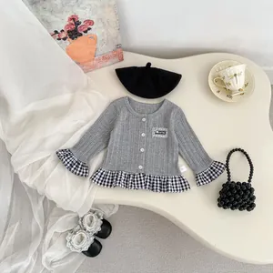 Detail van gebreid vest voor babymeisjes met grijze ribstructuur en geruite ruches aan de zoom