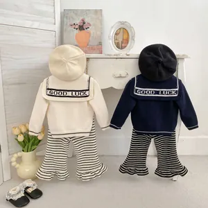 Detail of knitted girls' cardigan collar with GOOD LUCK embroidery and striped pants