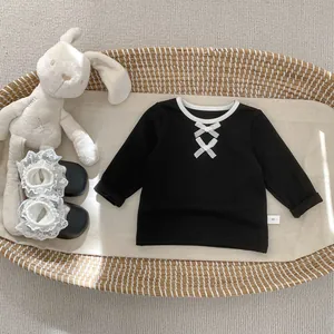Dettaglio top in cotone nero per bambina con fiocchi bianchi e scarpe in pizzo