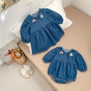 Detail of embroidered Peter Pan collar on denim dress with cute rabbit and puppy motifs