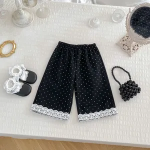 Pantaloni a gamba larga per bambina neri a pois bianchi con bordo in pizzo