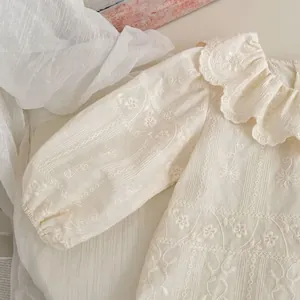 Dettaglio della camicetta neonata panna con ricamo floreale e colletto in pizzo smerlato