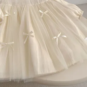 Detail of layered tulle skirt with satin bows on a cream girls princess dress