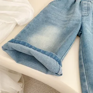 Detailed close-up of light blue kids' denim jeans featuring folded cuffs and faded wash