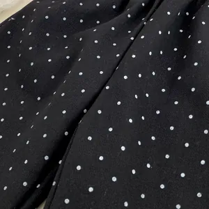 Dettaglio del tessuto a pois neri e bianchi con trama saia per pantaloni da bambina