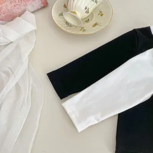 Dettaglio delle cuciture delle maniche raglan bicolore sulla maglia in cotone da bimba
