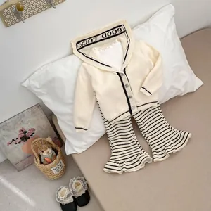 Detail of baby knit cardigan with GOOD LUCK hood and striped flared trousers set