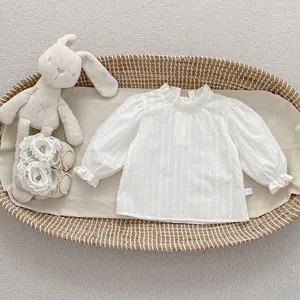 Detail of baby cream long sleeve cotton shirt with ruffle neck and vertical texture