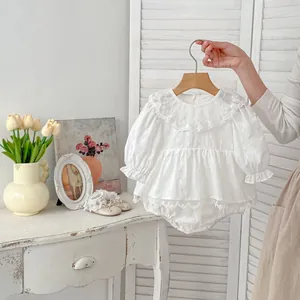 Detailed close-up of white baby bodysuit featuring delicate lace collar and frill cuffs