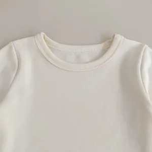Macro shot of cream ribbed knit fabric and reinforced crew neckline on baby shirt