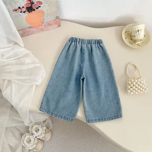 Flat lay of light blue kids wide-leg denim jeans with elastic waist and floral decor