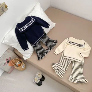 Detailed flat lay of knit sweaters and striped flared pants for girls on a cozy bed