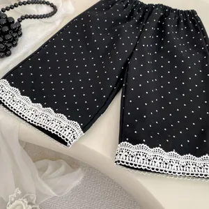 Dettaglio dei pantaloni larghi a pois neri per bambina con bordo in pizzo bianco
