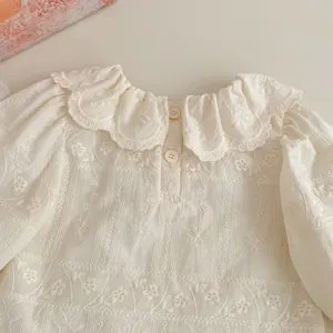 Dettaglio della camicetta da neonata in cotone bianco con ricamo e colletto a smerlo