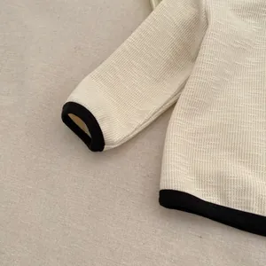 Macro detail of toddler cream waffle knit top with black contrast binding and soft texture