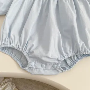 Detail of light blue baby romper with bottom snap buttons and soft ruffled hem design