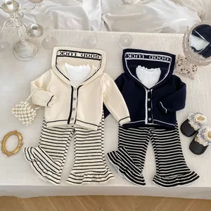 Detailed flat lay of girls' knitted sets with GOOD LUCK lettered cardigans and striped pants