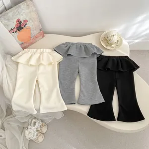 Dettaglio di pantaloni svasati con volant in vita per bambina nei colori crema, grigio e nero