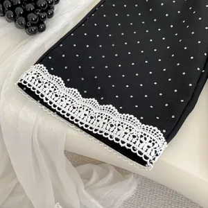Pantaloni a gamba larga a pois neri da bambina con bordo in pizzo bianco per la primavera