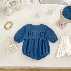 Detail of baby denim romper with turn-down collar and side care label on white texture