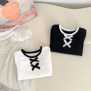 Dettaglio di girocollo a contrasto e fiocchi decorativi su t-shirt in cotone per bambine