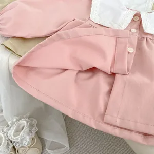Close-up of pink toddler dress with white lace collar and decorative buttons